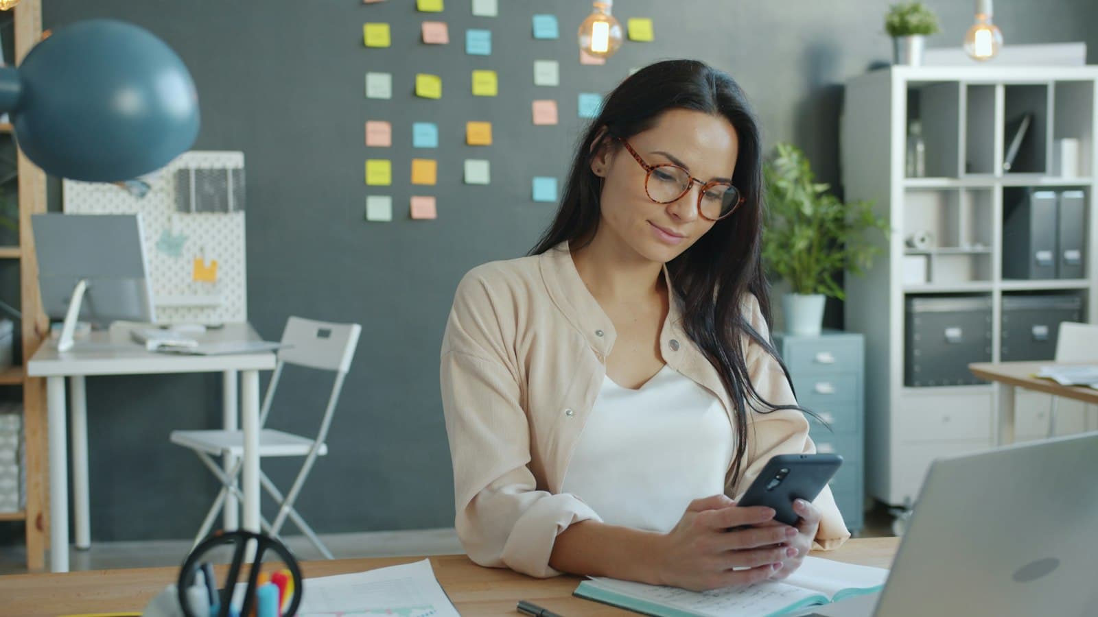 A smiling woman using her phone in an office